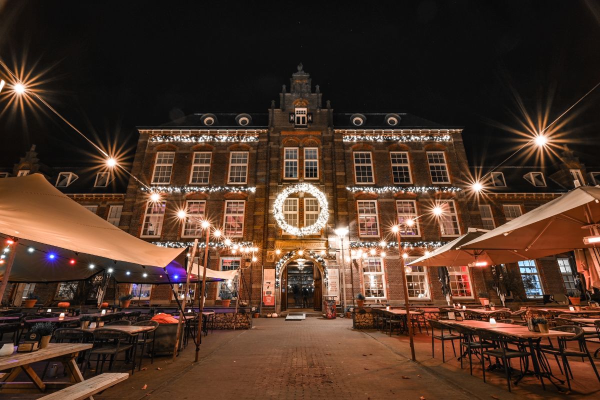De Krayenhoffkazerne bij nacht met verlichte krans, slingers en het terras in kerstsfeer.
