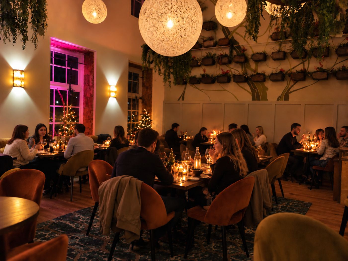 Gasten dineren bij kaarslicht in het restaurant van In de Kazerne, met kerstbomen bij de ramen.